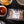 Cargar imagen en el visor de la galería, A vacuum-sealed package of Purple Ribbon Fully Cooked Ground Beef placed on a dark surface, surrounded by a bowl of red sauce, burger buns, and a striped cloth.
