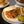 Cargar imagen en el visor de la galería, A plated sloppy joe sandwich with a sesame bun, served with french fries and pickles on a dark tabletop, with additional plates and a bowl blurred in the background.
