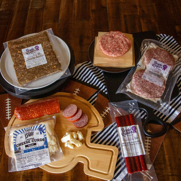 Assorted deli meats and cheeses on a wooden table with a plaid cloth.
